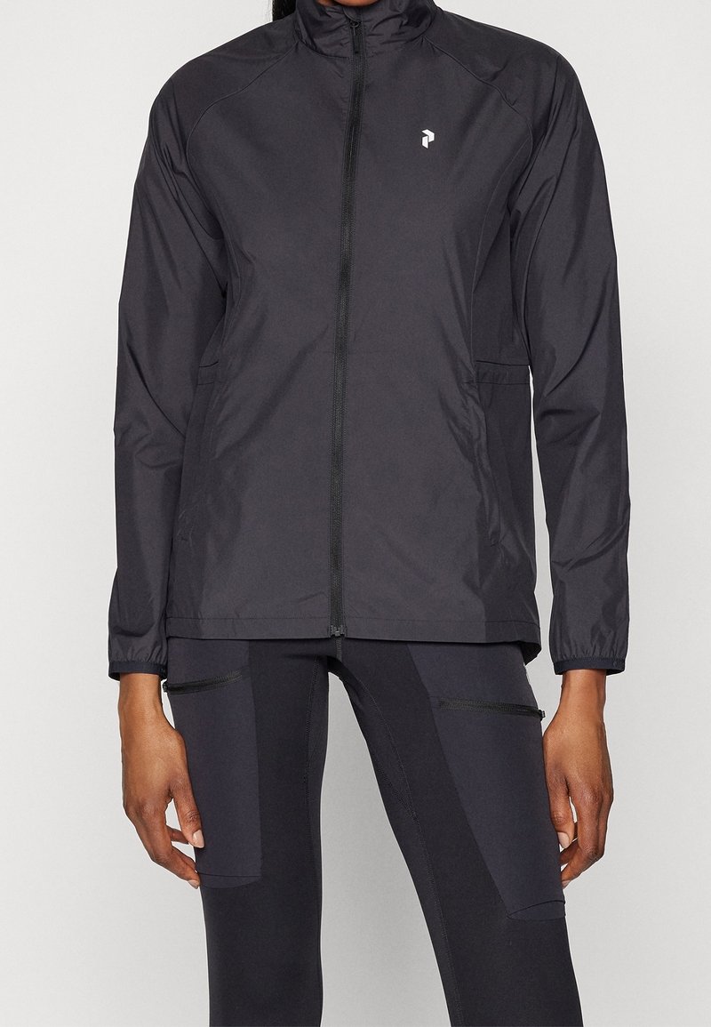 Veste noire légère avec un col montant, une fermeture éclair complète, deux poches latérales et un petit logo sur le côté gauche de la poitrine. Fabriquée en matière lisse et résistante à l'eau.