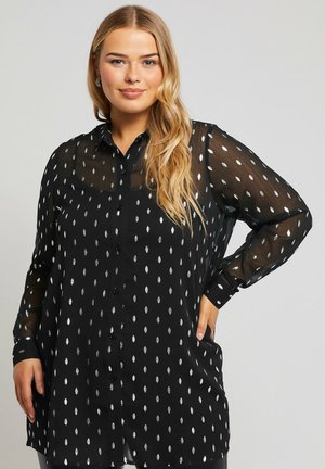 Blouse noire à manches longues en voile transparent, ornée de motifs de feuilles argentées à pois, avec des boutons sur le devant et une coupe décontractée. Tissu doux avec un léger éclat.