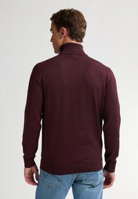 Burgunderfarbener Rollkragenpullover mit langen Ärmeln, gerippten Bündchen und Saum, weichem Stoff, von hinten vor einem hellen Hintergrund gezeigt.