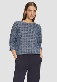 Marineblaues Tweed-Oberteil mit Dreiviertelärmeln, einem Rundhalsausschnitt und dekorativen Knöpfen an der Schulter. Strukturierter Stoff mit Karomuster.