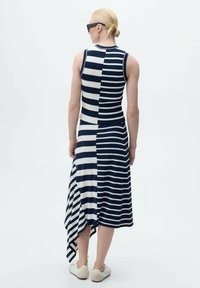 Mouwloze jurk met marineblauwe en witte strepen, voorzien van een high-low zoom en ribbelstructuur. Glad materiaal met een nauwsluitend ontwerp.