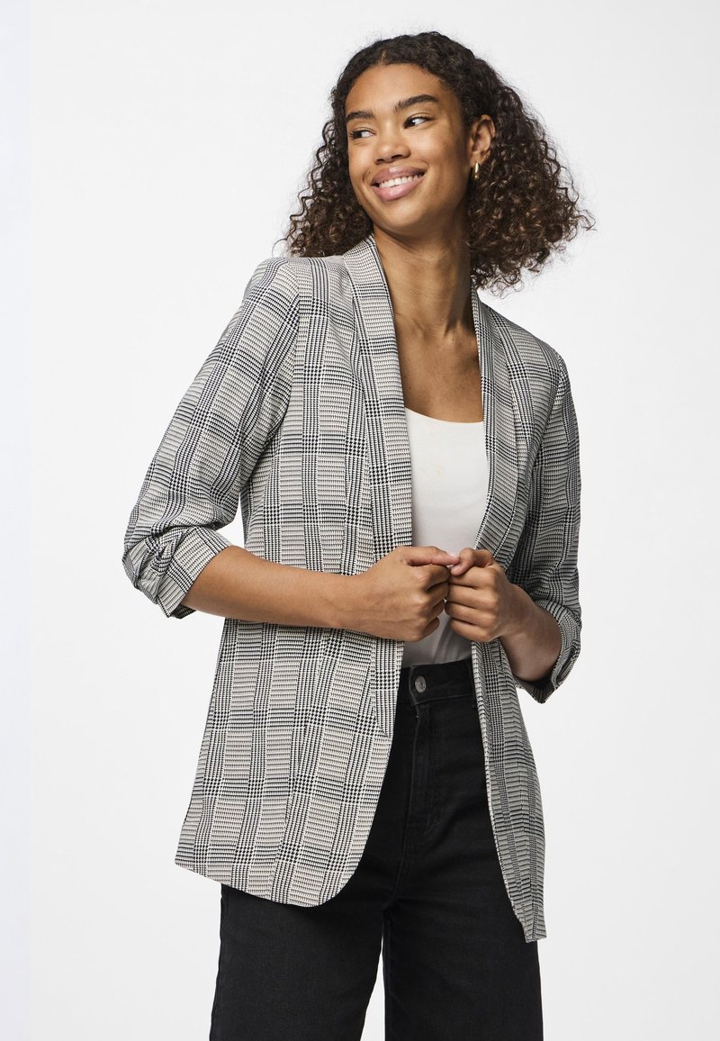 Blazer com padrão xadrez preto e branco, em tecido leve com corte descontraído, apresenta lapelas de entalhe e mangas dobradas.