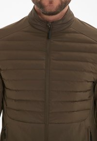 Brown insulated jacket with a zippered front, featuring horizontal quilted patterns, standing collar, and side pockets. Smooth texture.