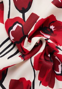 Rood bloemenpatroon stof heeft grote papaverontwerpen op een crème achtergrond, met een gladde, lichte textuur en subtiele glans.