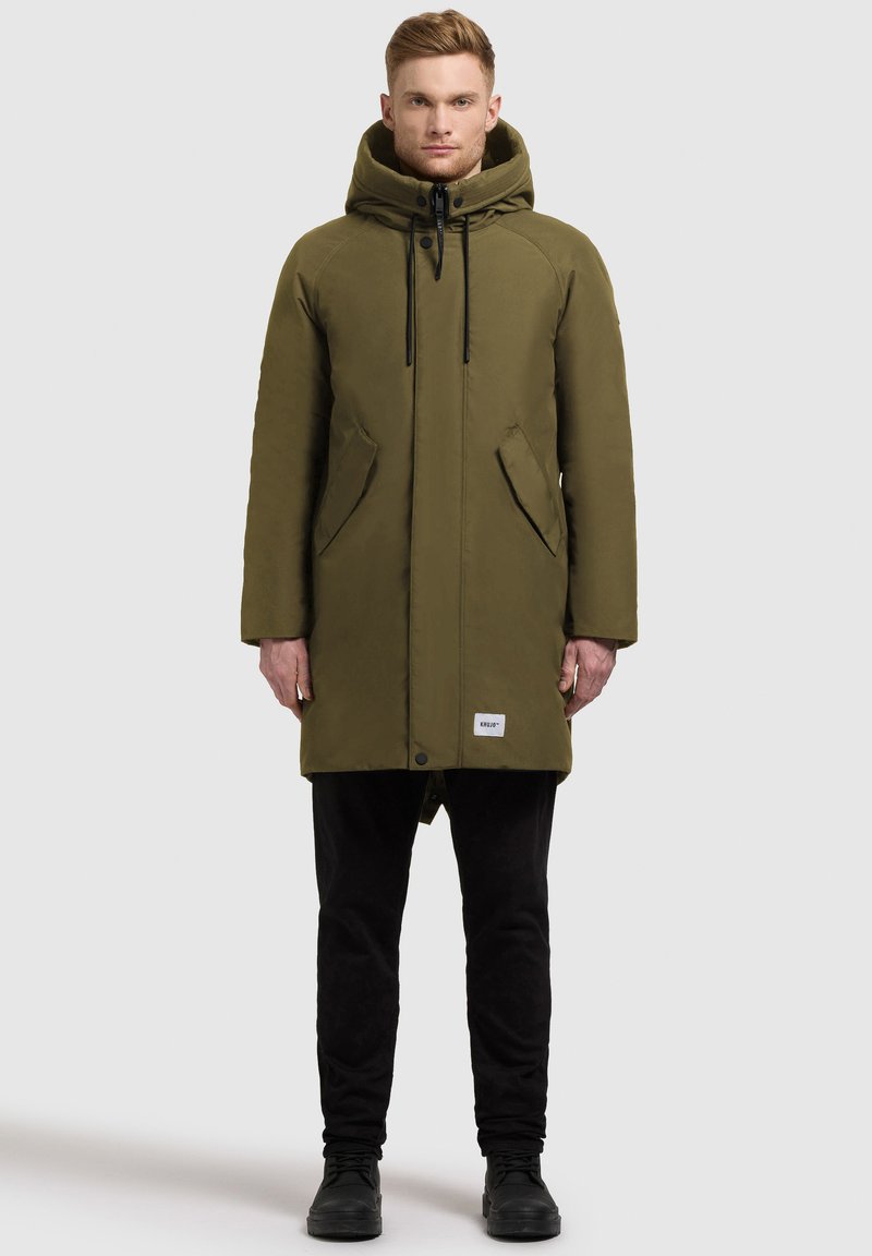 Olīvu zaļš parka mētelis ar kapuci, priekšējo spiedpogu aizdari un divām sānu kabatām, izgatavots no teksturēta ūdensizturīga materiāla.
