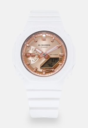 Ceas G-SHOCK de la Casio, cu curea din rășină albă, un cadran roz-aurie cu display analogic-digital și rezistență la apă de până la 200 de metri.