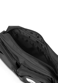 Primo piano di una borsa nera con vari scomparti con zipper, che mostra una fodera interna e una texture, progettata per una conservazione organizzata.