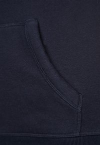 Mörkblå sweatshirttyg med en känguruficka framtill. Mjuk textur och ribbad detaljer vid nederkanten.