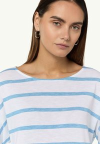 Weißes T-Shirt mit horizontalen blauen Streifen, mit weitem Ausschnitt und kurzen Ärmeln. Glatte Baumwolltextur, lässiger Schnitt.