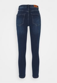 Jeans skinny azul oscuro con una textura de denim suave, que cuentan con dos bolsillos traseros y una etiqueta de cuero marrón en la cintura.