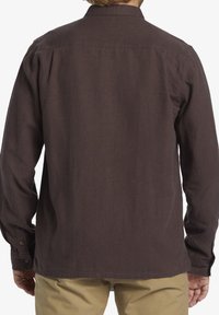 Brown long-sleeve shirt made of textured fabric, featuring a button-down collar and cuffs, with a straight hem and subtle stitching details.