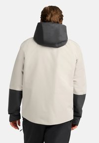 Leichte wasserdichte Jacke in Beige mit einer dunkelgrauen Kapuze und Ärmeln. Sie hat eine glatte Textur und einstellbare Bündchen für zusätzlichen Komfort.