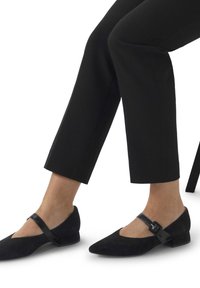 Schwarze Wildlederschuhe mit spitzem Zehenbereich und niedrigem Absatz. Besitzen einen dünnen schwarzen Riemen über den Spann mit einer Schnalle.