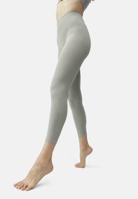 Leggings grigi chiaro con una vita alta, realizzati in materiale elasticizzato; presentano dettagli ritagliati vicino alla caviglia e un design senza cuciture.