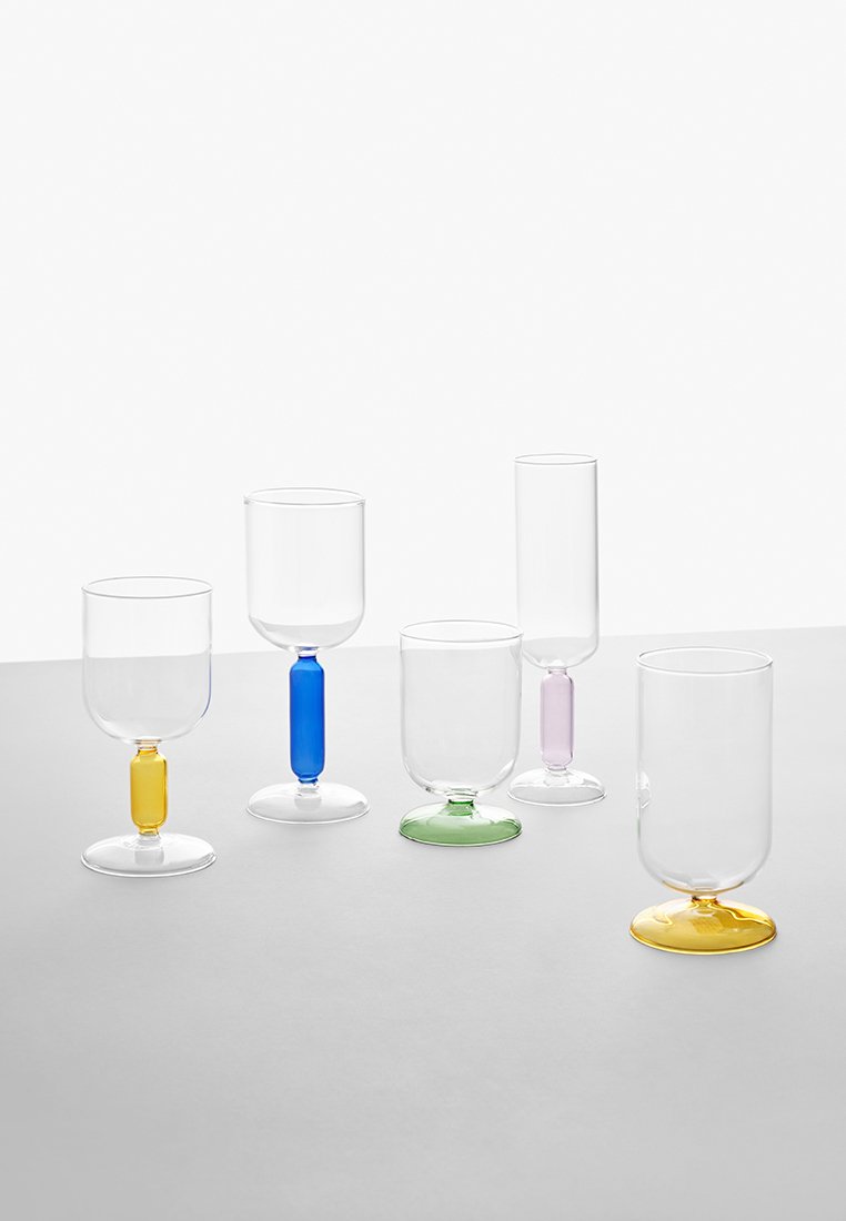 Zestaw pięciu przezroczystych szklanych naczyń do picia z kolorowymi podstawami i nogami w niebieskich, zielonych, żółtych i fioletowych akcentach. Różne kształty i wysokości.