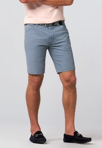 Light blue shorts with a smooth texture, featuring side pockets and a fitted design. Worn with a patterned belt and dark shoes.