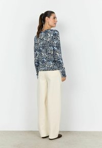 Bluză cu mânecă lungă, culoare bleumarin, cu imprimeu floral în albastru deschis și crem, asortată cu pantaloni largi albi. Material neted și croială lejeră.