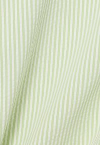 Tissu rayé vert clair et blanc avec une texture lisse, présentant de fines lignes verticales et un tombé doux.