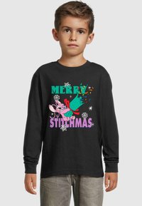 Fekete, hosszú ujjú póló, amelyen színes felirat olvasható: "MERRY STITCHMAS", valamint egy karikatúra figura ünnepi pózban, hópehely grafikákkal.