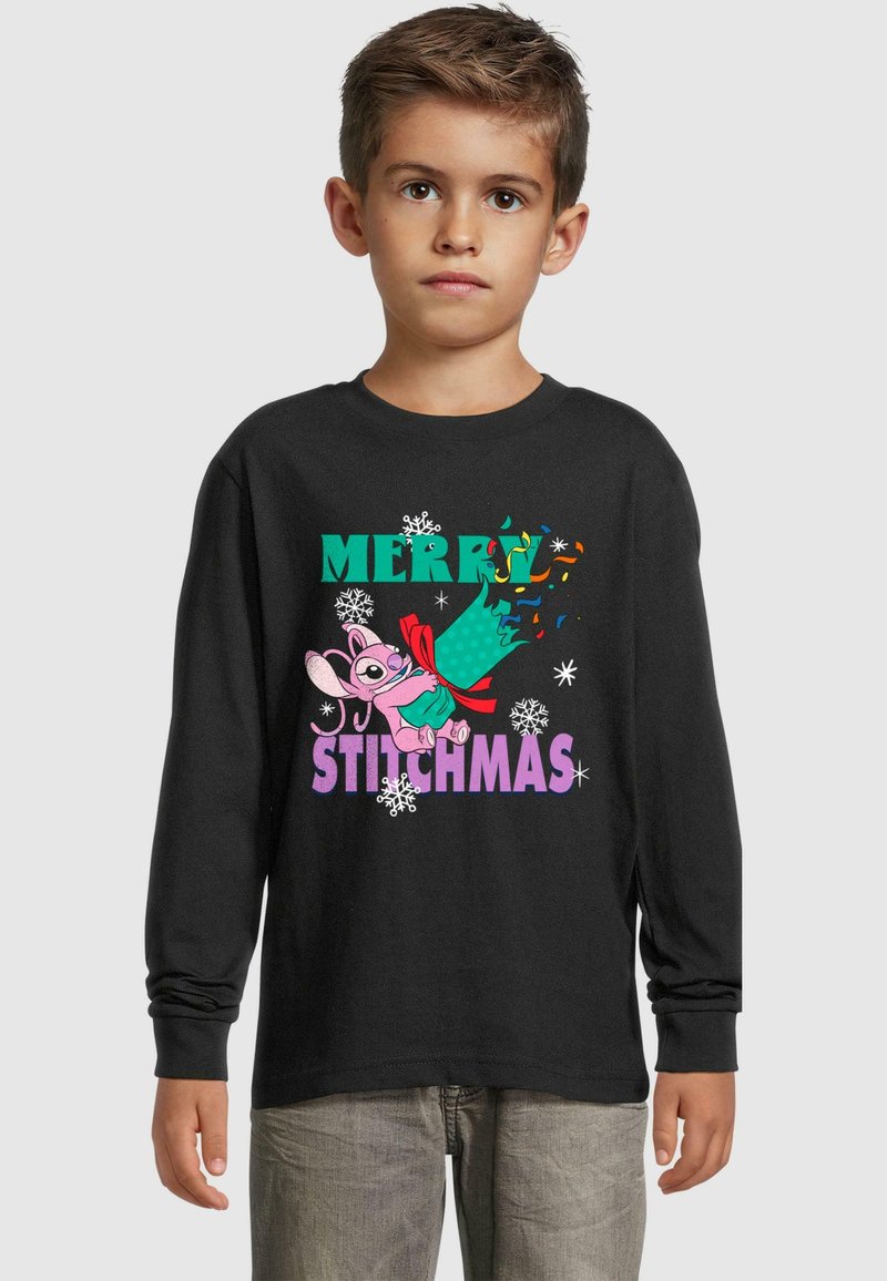 Fekete, hosszú ujjú póló, amelyen színes felirat olvasható: "MERRY STITCHMAS", valamint egy karikatúra figura ünnepi pózban, hópehely grafikákkal.
