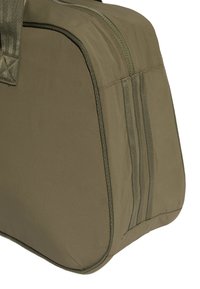 Khaki-stoff duffelbAg med rektangulær form, med glidelås lukking og tre vertikale sømstriper på den ene siden.