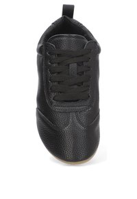 Zapato de cuero negro con superficie texturizada, puntera redonda, diseño de cordones y suela de goma. Cuenta con una lengüeta en el talón para facilitar el uso y desuso.