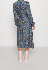 Floral print dress with long sleeves and a tie waist, featuring multiple colors on a dark background. Paired with light pink ankle boots.