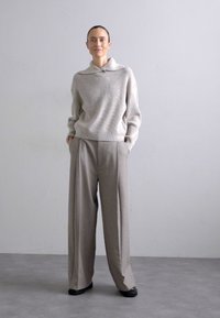 Light gray ribbed sweater with a wide collar, paired with high-waisted wide-leg beige trousers. Textured fabric and relaxed fit.