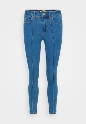 Modré džíny skinny mají vysoký pas, přední kapsy a kontrastní prošívání podél švů. Celkově hladká textura.