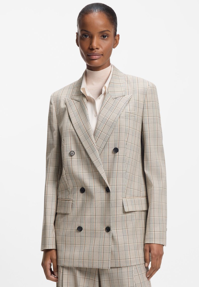 Beige ternet dobbeltradet blazer med sorte knapper, store revers og to forlommer. Glat stof med en struktureret pasform.