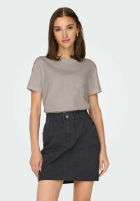 Ljust grå bomullströja med en texturerad ficka, kombinerad med en mörk denimkjol med elastisk midja och sidofickor.