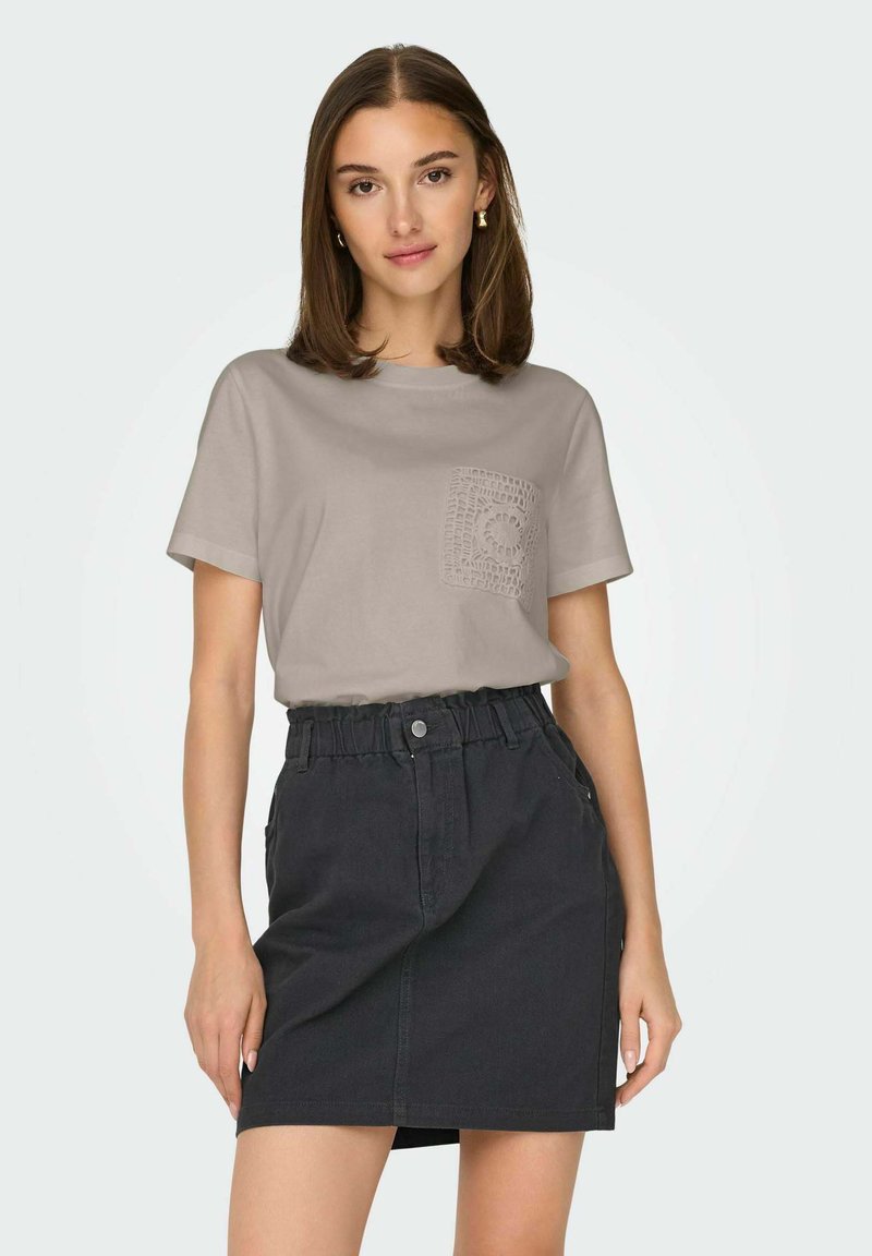 Ljust grå bomullströja med en texturerad ficka, kombinerad med en mörk denimkjol med elastisk midja och sidofickor.