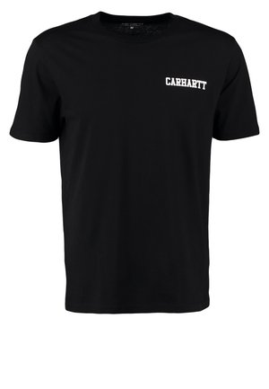 Mand iført sort Carhartt t-shirt, revne denimshorts, hvide sneakers, holder en sort rygsæk i den ene hånd, står mod en lys baggrund.