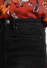 Svarta denimjeans med hög midja, femfickorsdesign och detaljer i silverfärg. Tyget har en mjuk textur.