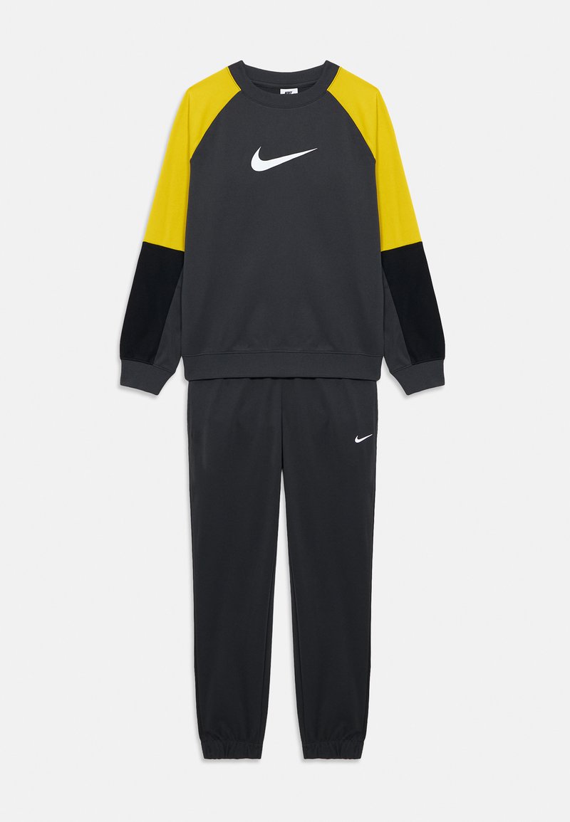 Sweatshirt gris avec des accents jaunes et noirs, arborant un logo Nike blanc. Assorti à un pantalon de jogging gris, avec des poignets élastiques.