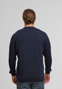 Maglione blu navy con maniche a treccia testurizzate, polsini e scollo a costine, e un corpo liscio. Tessuto a maglia con una vestibilità comoda.