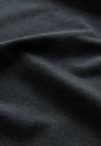 Svart tyg med en mjuk textur, som har subtila veck och en matt finish. Ytan verkar jämn utan mönster eller utsmyckningar.