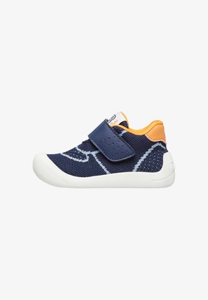 Marineblaue Mesh-Kinderschuhe mit weißer Gummisohle, orangefarbenem Akzent an der Ferse und Klettverschluss. Verfügt über seitliche Belüftungslöcher für Atmungsaktivität.