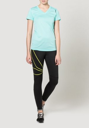 Světle modré atletické tričko s výstřihem do V v kombinaci s černými legínami s žlutými zakřivenými pruhy. Oba kousky jsou vyrobeny z elastických a prodyšných materiálů.