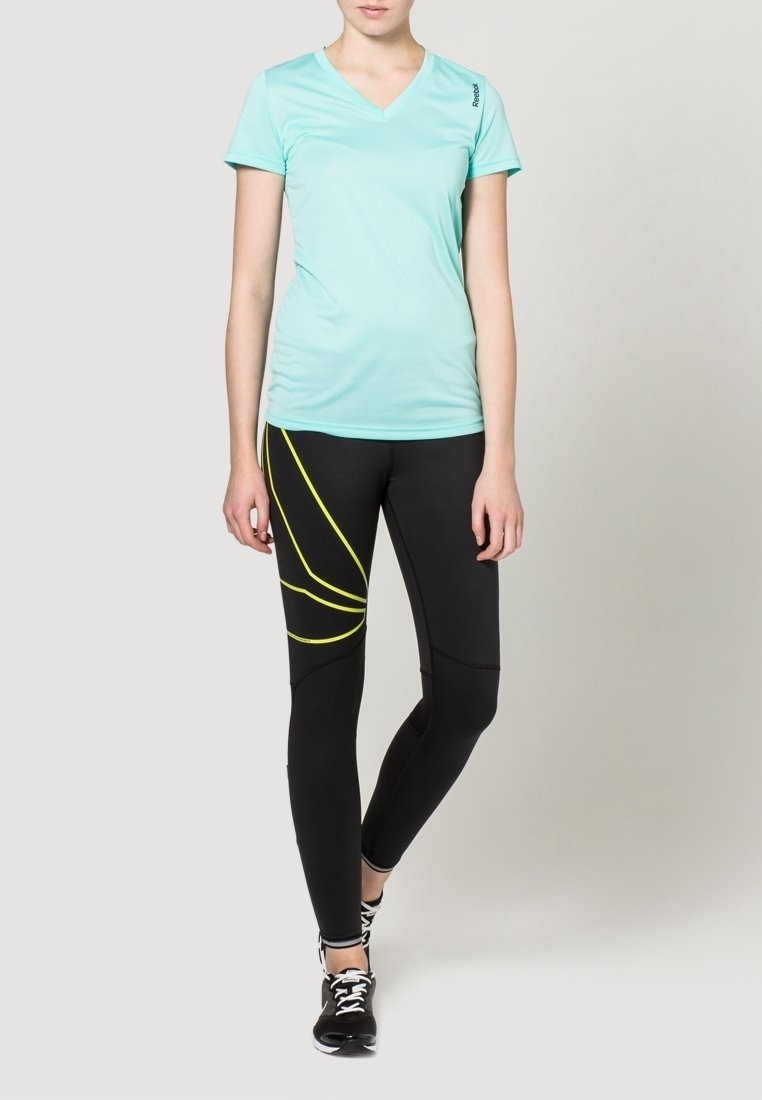 Hellblaues, v-förmiges Sportshirt kombiniert mit schwarzen Leggings, die gelbe geschwungene Streifen aufweisen. Beide sind aus dehnbaren, atmungsaktiven Materialien gefertigt.