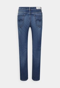 Jeans z ciemnego denimu o prostym kroju nogawki, z dwiema tylnymi kieszeniami w zygzakowaty wzór oraz metką z logo na pasku.