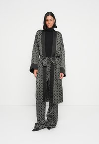 Mustast mustriga rüü laiade varrukatega ja sobivate pükstega, millel on hall geomeetriline muster. Kangas on siledat tekstuuri ja vööga, mida saab lipsutada.