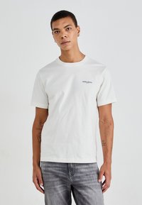 Hvit bomull T-skjorte med rund hals og korte ermer, som har en liten svart "PEPE JEANS" logo på venstre bryst.