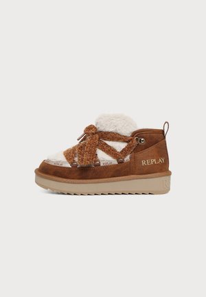 Bottine Replay marron à épaisse semelle beige, doublure en fausse fourrure crème et gros lacets tricotés bruns, sur un fond uni.