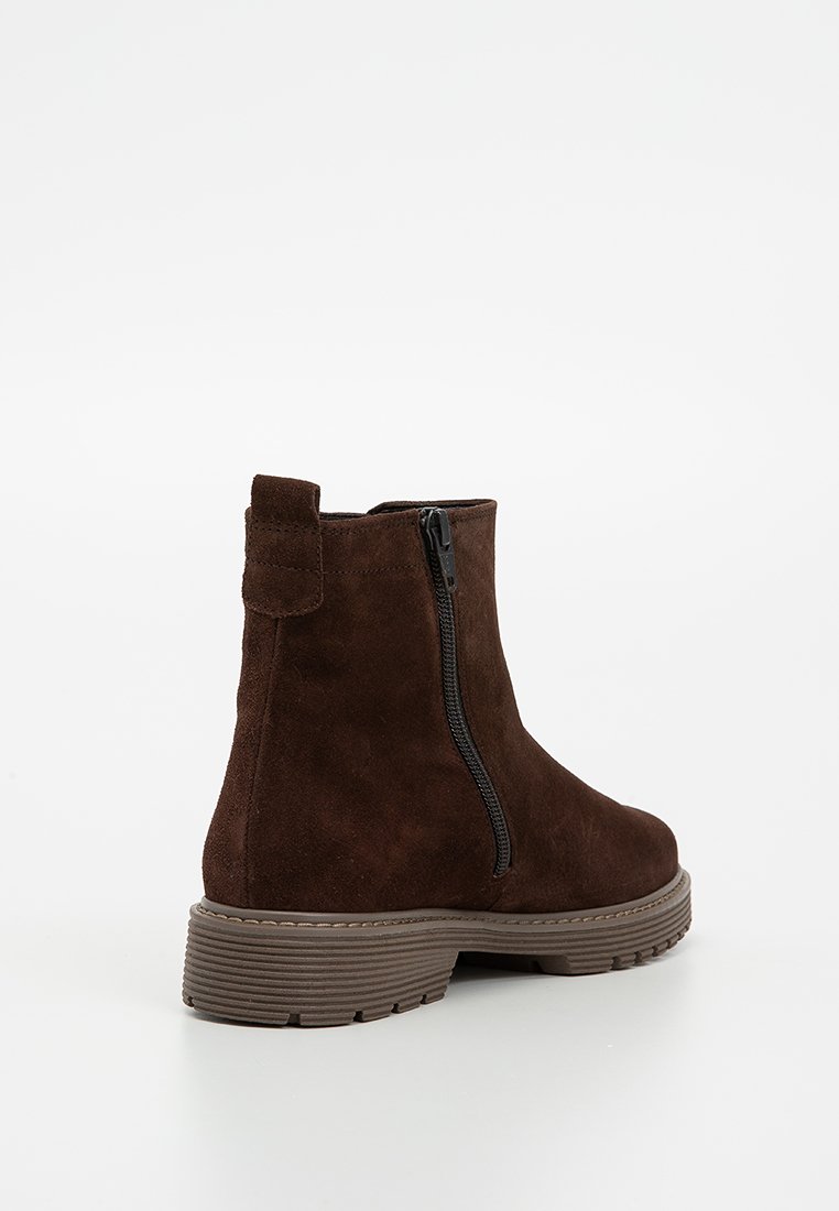 Donkerbruin suède enkellaars met een zijrits, trekband en dikke gegroefde rubberen zool, gezien vanaf de zijkant op een eenvoudige witte achtergrond.