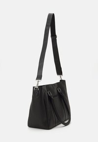 Μαύρη δερμάτινη τσάντα με υφή, διπλές λαβές, αποσπώμενος ιμάντας ώμου και ασημί μεταλλικά στοιχεία. Διαθέτει μια τσέπη με φερμουάρ.