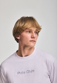 Jasnofioletowa bluza z okrągłym dekoltem, z subtelnym napisem "Polo Club". Wykonana z miękkiej bawełny, o luźnym kroju.