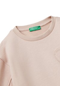 Sudadera beige de cuello redondo con cuello acanalado y etiqueta verde "United Colors of Benetton" en el interior del escote.
