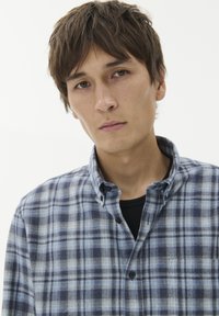 Mėlynos ir baltos kvadratinės raštos marškiniai su minkšta tekstūra. Yra klasikinė apykaklė ir viena krūtinės kišenė.