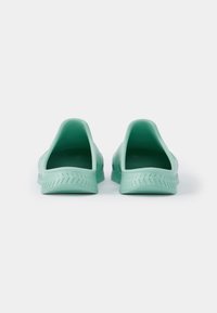 Sapatos slip-on verdes menta com abertura na parte de trás, apresentando uma sola texturizada e uma superfície exterior lisa. Design leve e flexível.